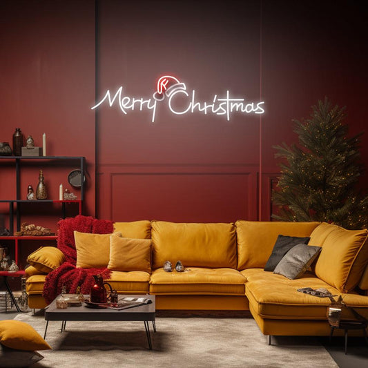 Red and white Merry Christmas LED neon sign above a mustard sofa beside a decorated Christmas tree